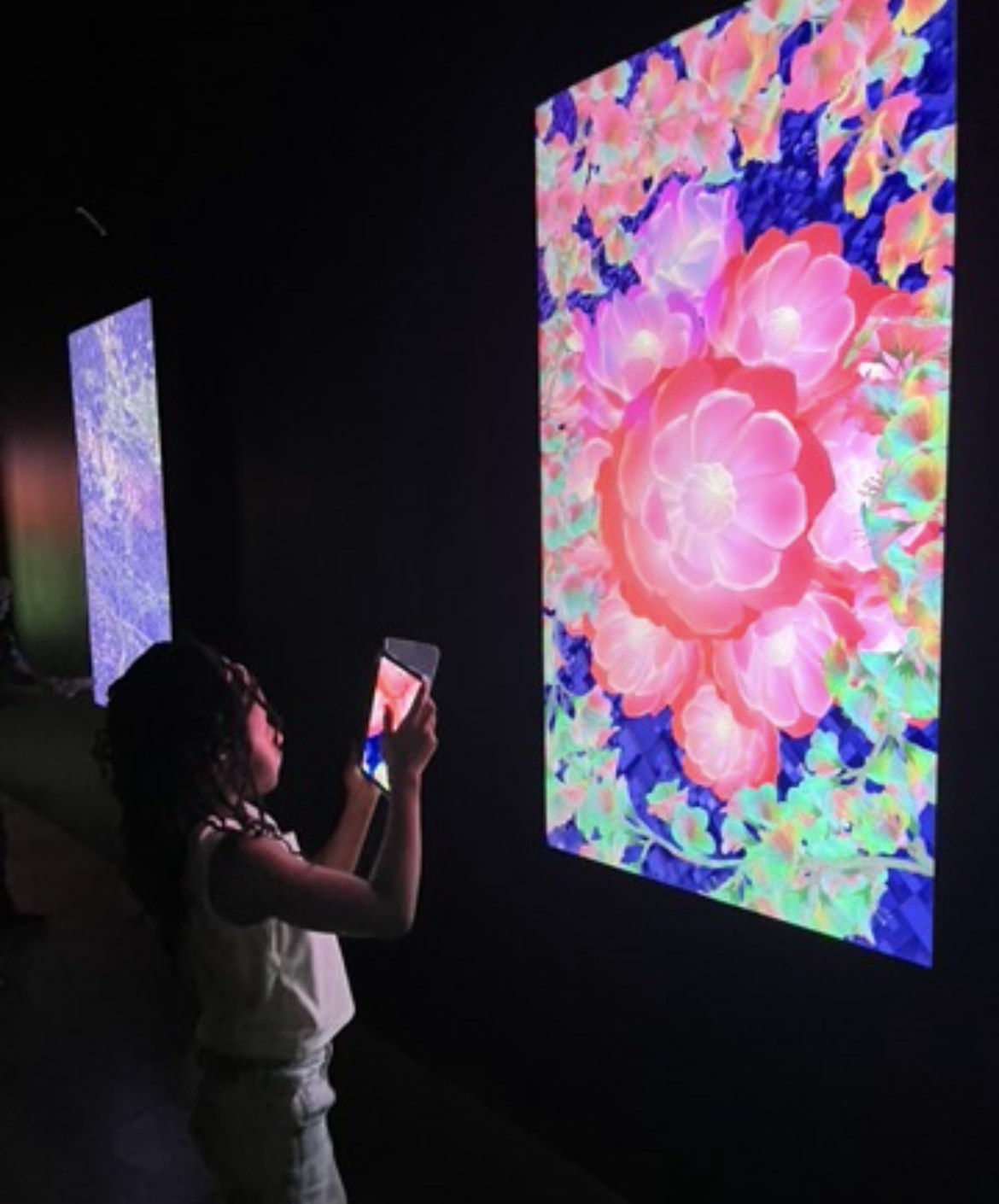 A student photographing a glowing digital art installation